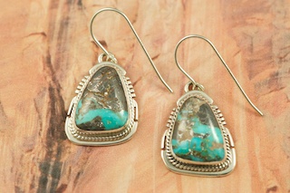 Genuine Sunnyside Turquoise set in Sterling Silver French Wire Earrings. The matrix on this rare stone is outstanding. The Sunnyside mine is located in northern Nevada near the town of Tuscarora in the Tuscarora mountain range. The mine is no longer in operation as it has become part of a gold mining operation and a privately owned ranch. The Sunnyside mine was mined mostly in the 70's. You won't find much of this great turquoise around anymore except for old stashes. Created by Navajo Artist Larson Lee. Signed by the artist.